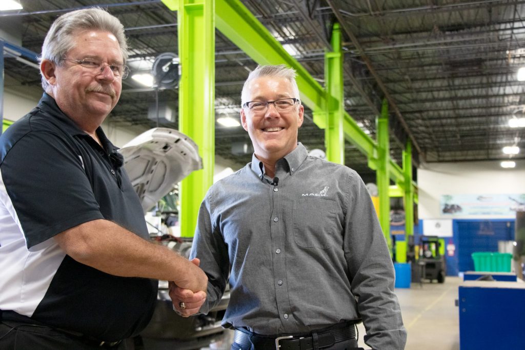 Two men shaking hands in automotive school